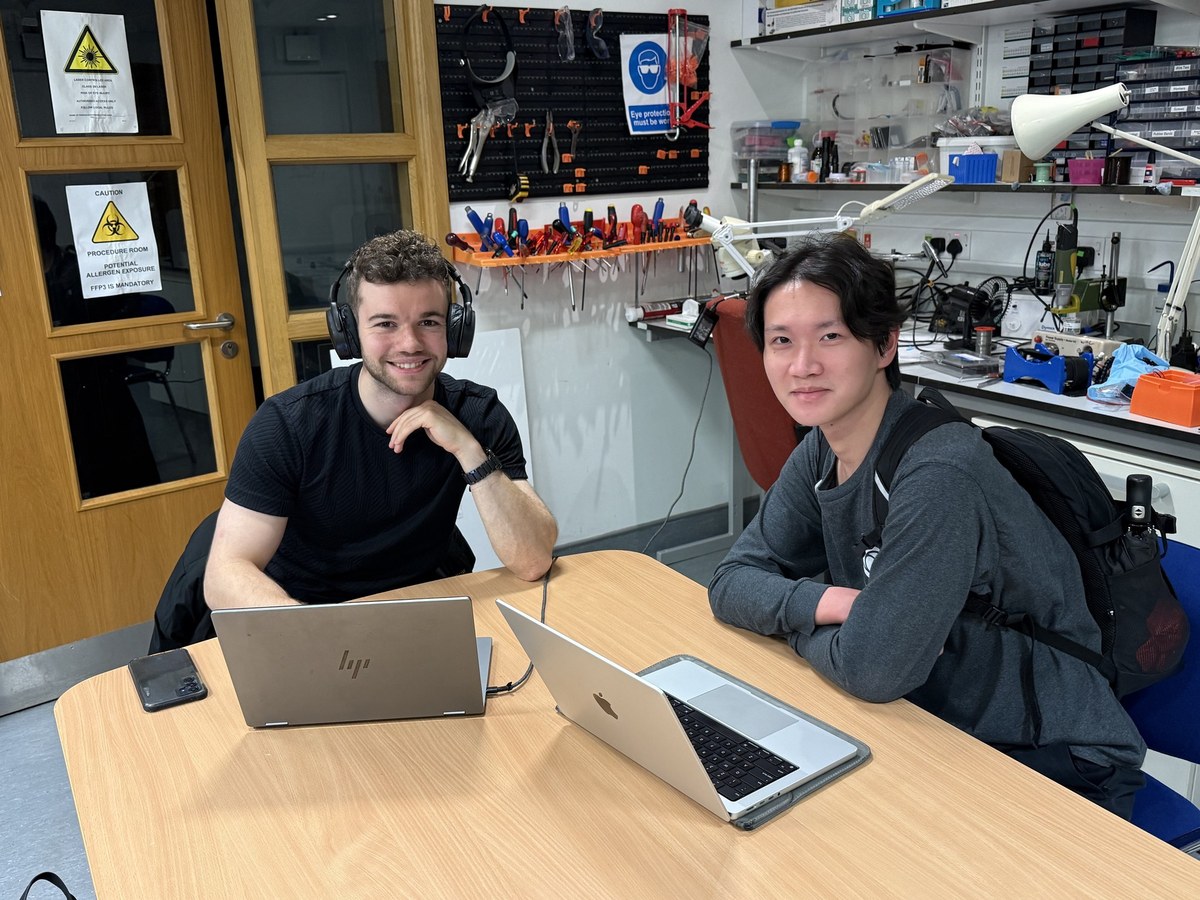 Bernd Alexander Breuer and Yiqun Li sitting at a bench in the lab with their laptops